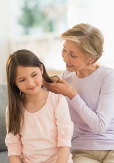 Grandmother brushing granddaughter's (8-9) hair.