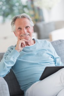 Senior man sitting on sofa with digital tablet.