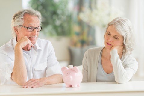 Senior couple looking at piggybank.