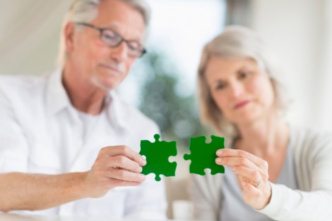 Senior couple holding matching jigsaw pieces.