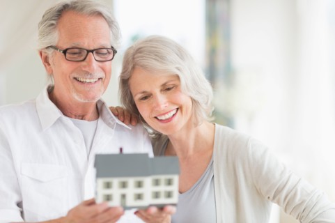 Senior couple holding model house.