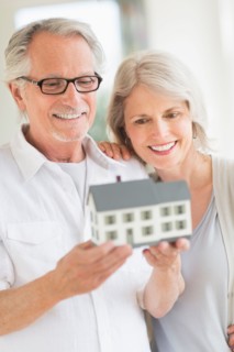 Senior couple holding model house.