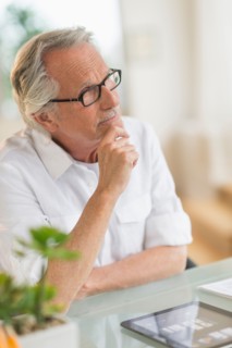 Portrait of senior man thinking at desk.