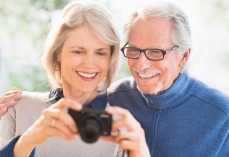 Smiling senior couple with digital camera.