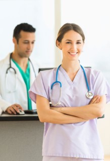 Female and male nurses at nurse's station in hospital.