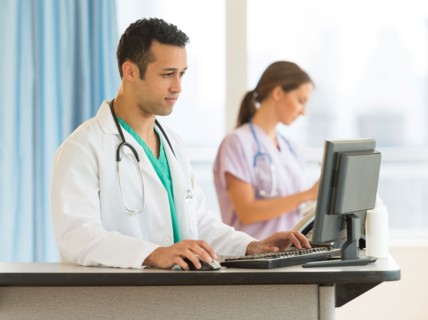 Male and female nurses working at nurse's station in hospital.