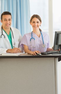 Portrait of male and female nurses at nurse's station in hospital.