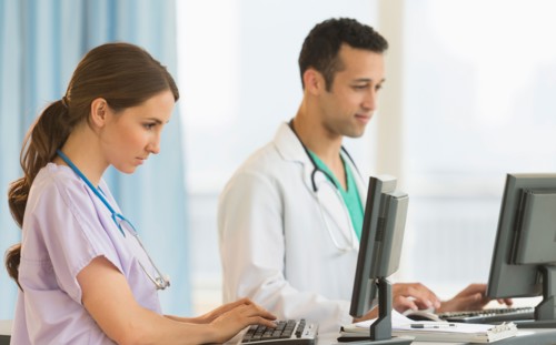 Male and female nurses working at nurse's station in hospital.