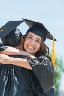 Female and male student embracing on graduation ceremony.