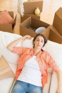 Young woman resting on sofa after moving into new home.