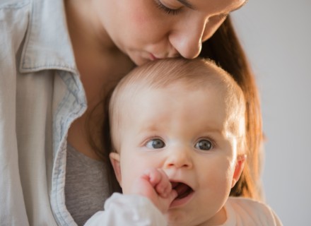 Mother kissing baby daughter (6-11 months)