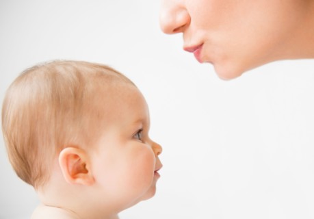 Side view of mother about to kiss her baby daughter (6-11 months)