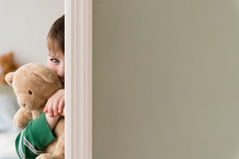Portrait of boy (4-5) hiding behind wall