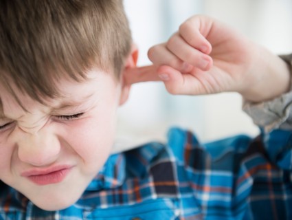 Portrait of boy (4-5) sticking fingers in his ears
