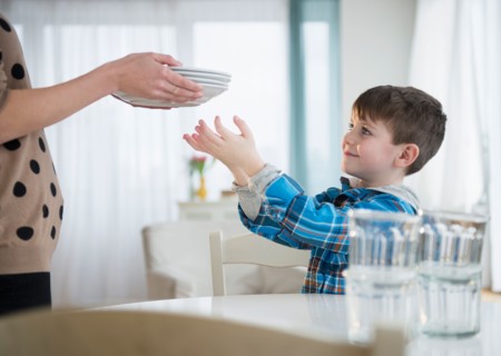 Boy (4-5) helping mother to set table