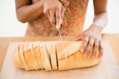 Close up of womaqn's hand cutting bread