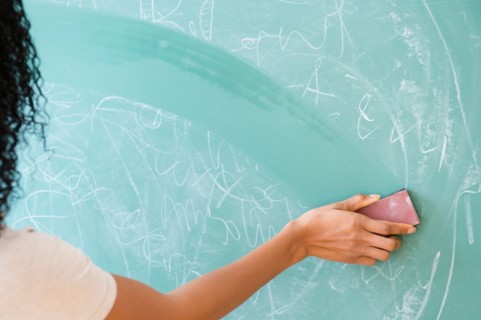 Rear view of woman erasing blackboard