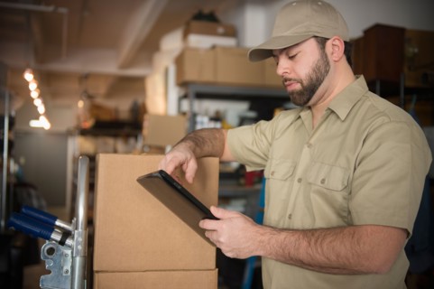 Delivery man in warehouse holding portable information device