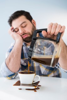Tired, sleepy man spilling coffee on table