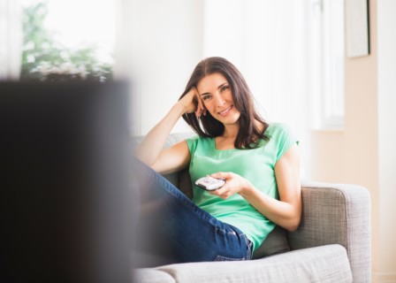 Portrait of woman watching TV on sofa