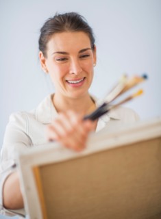 Studio Shot of woman holding paintbrushes and artist's canvas