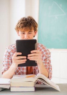 Teenage boy (14-15) sitting in classroom with tablet pc