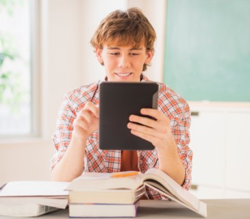 Teenage boy (14-15) sitting in classroom with tablet pc