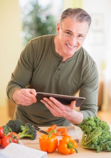 Portrait of man in kitchen, holding digital tablet