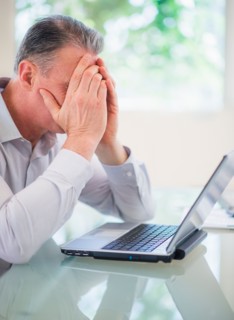 Portrait of tired man working on laptop