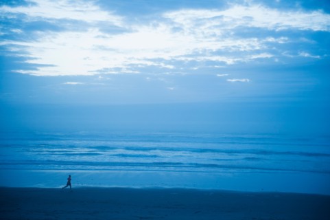 Distant view of woman running along beach