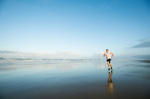 Young adult man running on beach