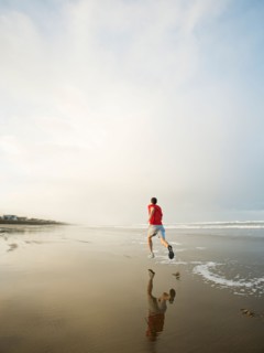Young adult man running on beach