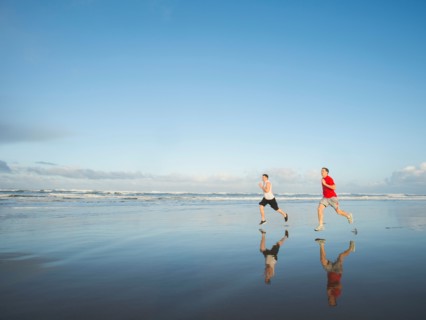 Young adult men running on beach