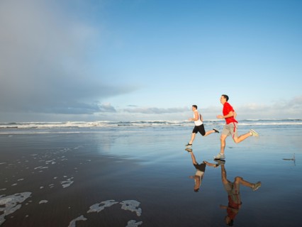 Young adult men running on beach