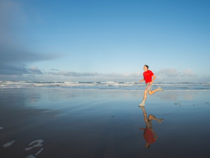 Young adult man running on beach