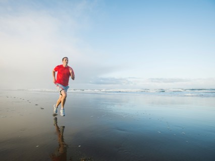 Young adult man running on beach