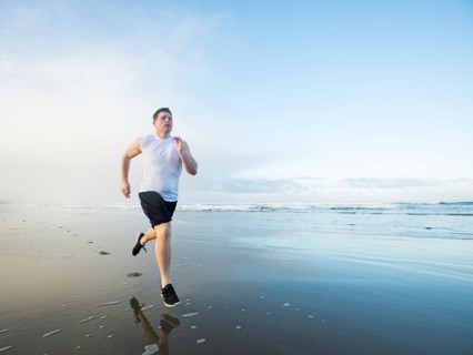 Young adult man running on beach