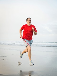 Young adult man running on beach