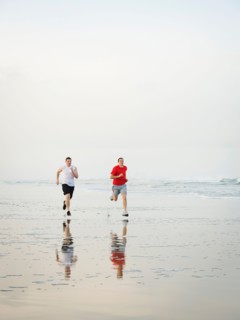 Young adult men running on beach