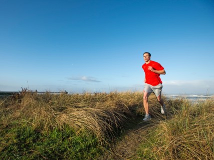 Young adult man running on dune
