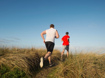 Young adult men running on dune