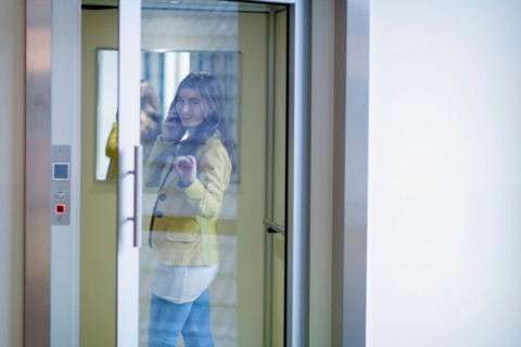 Woman opening glass door and talking on cell phone