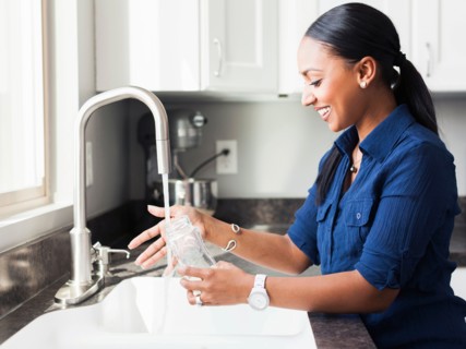Woman washing baby bottle in kitchen