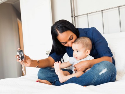 Mother sitting n bed with her son (2-5 months) taking a picture