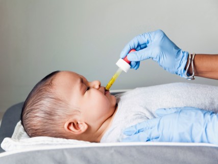 Nurse giving baby boy's (2-5 months) medicine using pipette