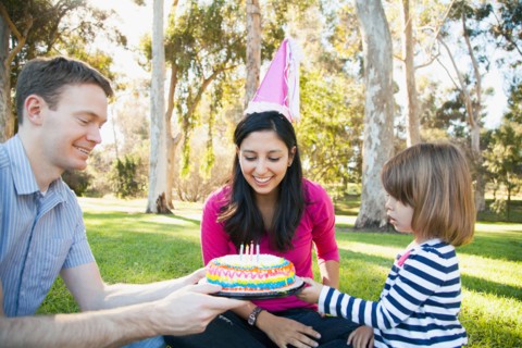 Portrait of happy family in park celebrating mother's birthday
