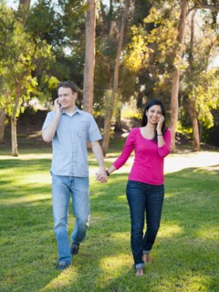 Couple walking and using mobile phone in park