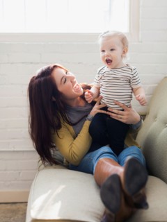 Mother and daughter (12-17 months) playing on sofa, Laughing and having fun
