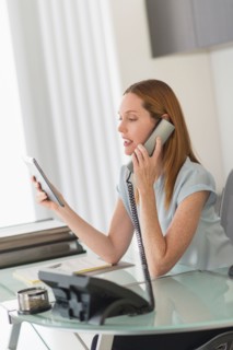 Business woman using phone and tablet pc in office.