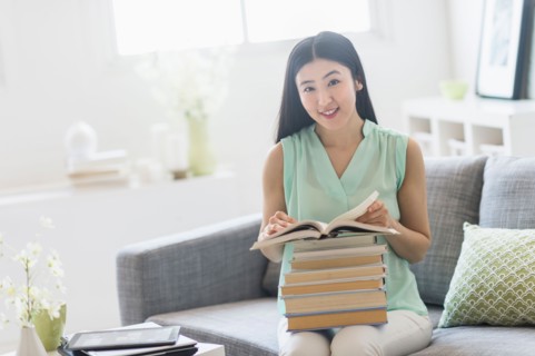 Woman with stack of books at home.